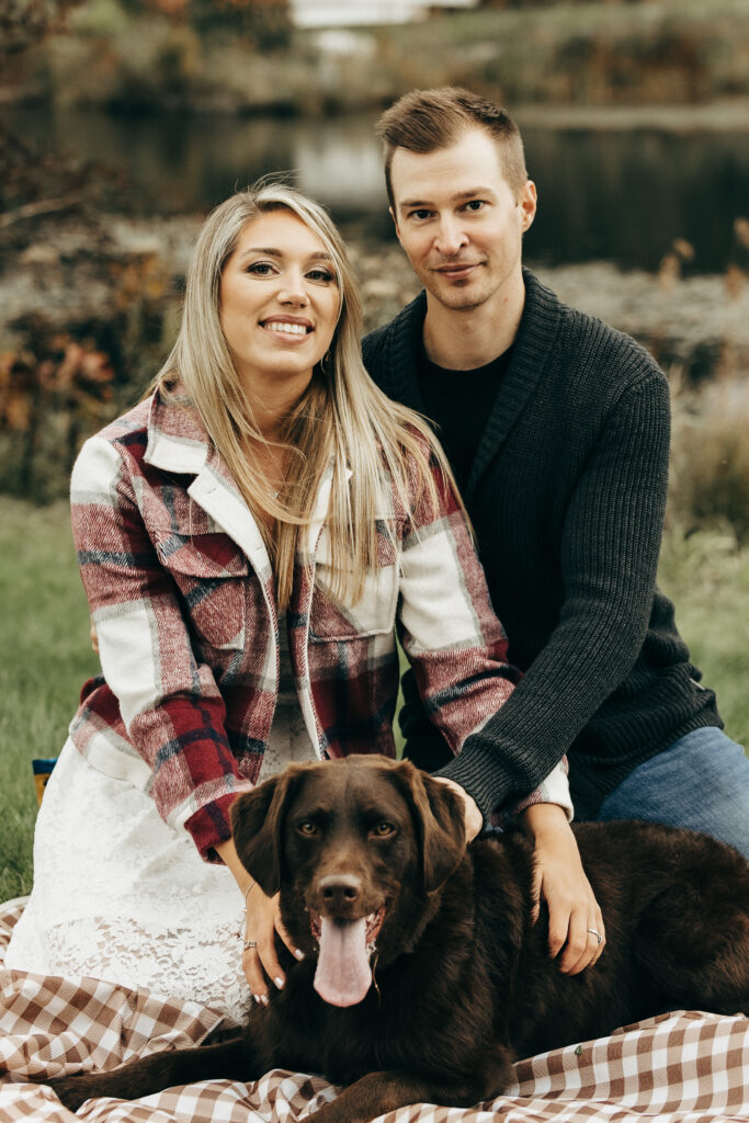 Couple posing with their dog during their engagement photography session. Vermont fall colors are popping. 