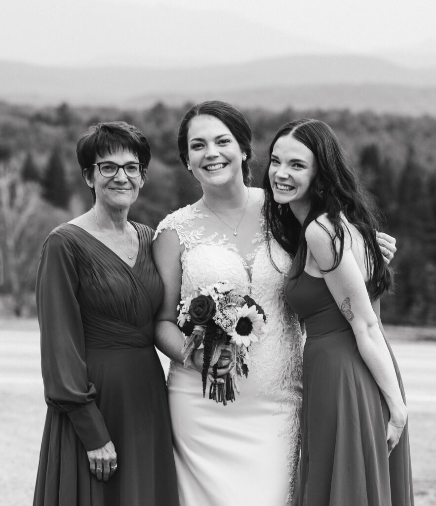 Bride and her sister posing with her mom during family formal photos at a wedding. Wedding is in Vermont 
