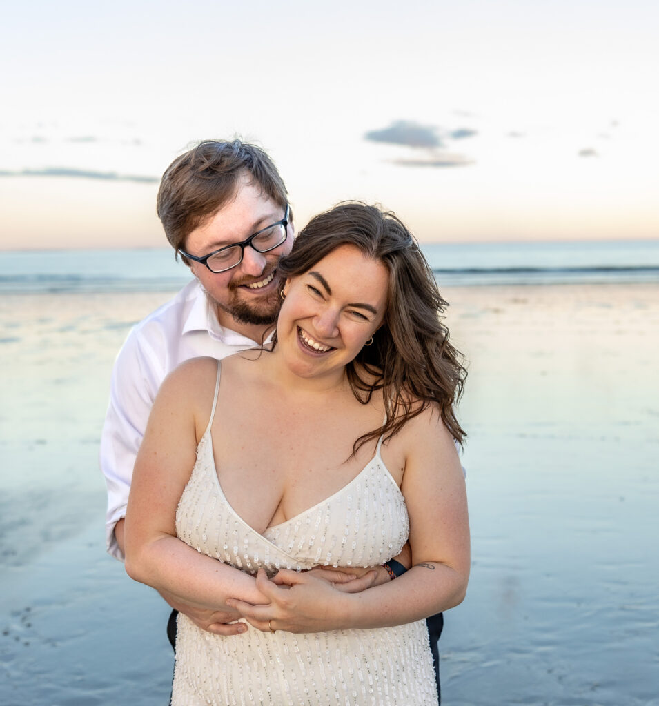couple holds each other while posing for elopement photos on Rye Beach. 